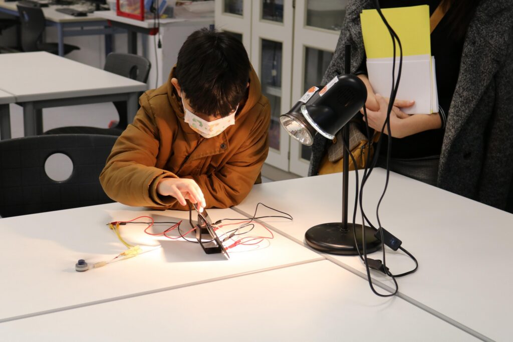 Ein Kind experimentiert mit elektrischen Bauteilen an einem Tisch.