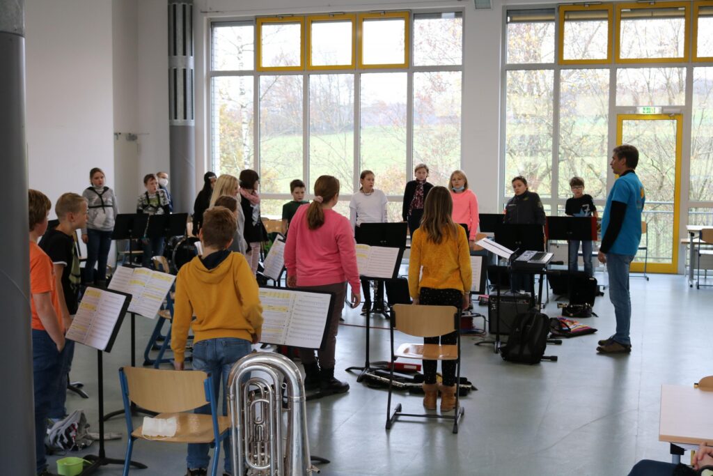 Schüler proben gemeinsam in einem großen Raum mit Instrumenten.