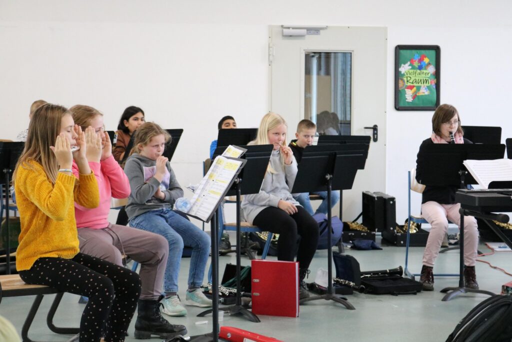 Schülerinnen proben mit Instrumenten in einem Klassenraum.