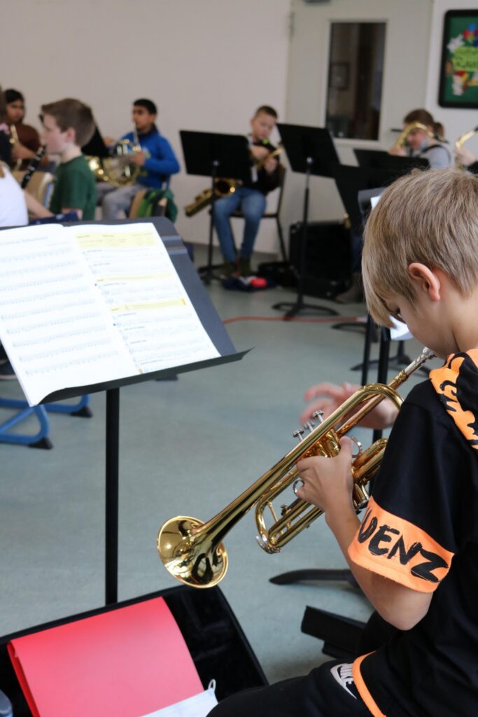 Schüler üben im Musikraum auf verschiedenen Blasinstrumenten.