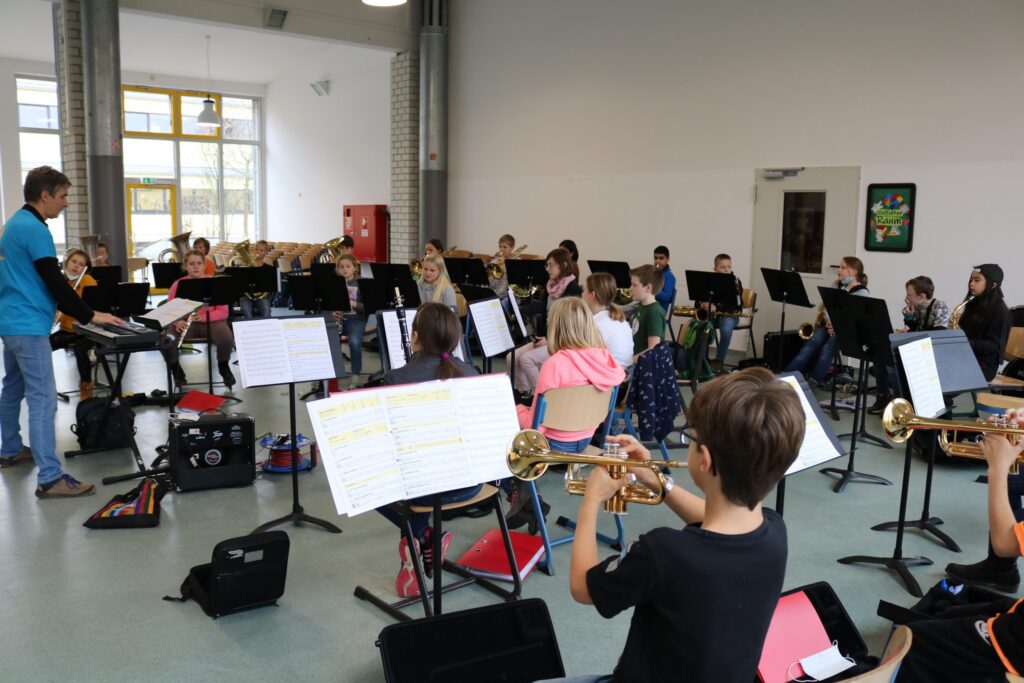 Proben einer Schülerband mit Instrumenten in einem hellen Raum.