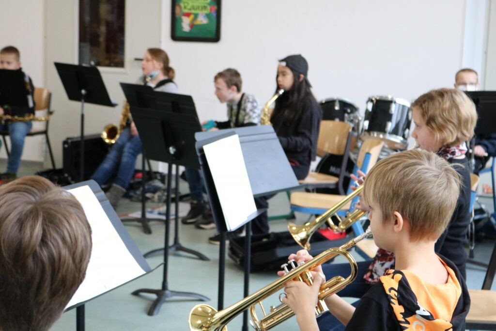 Schüler spielen in einem Musikraum Blasinstrumente im Orchester.