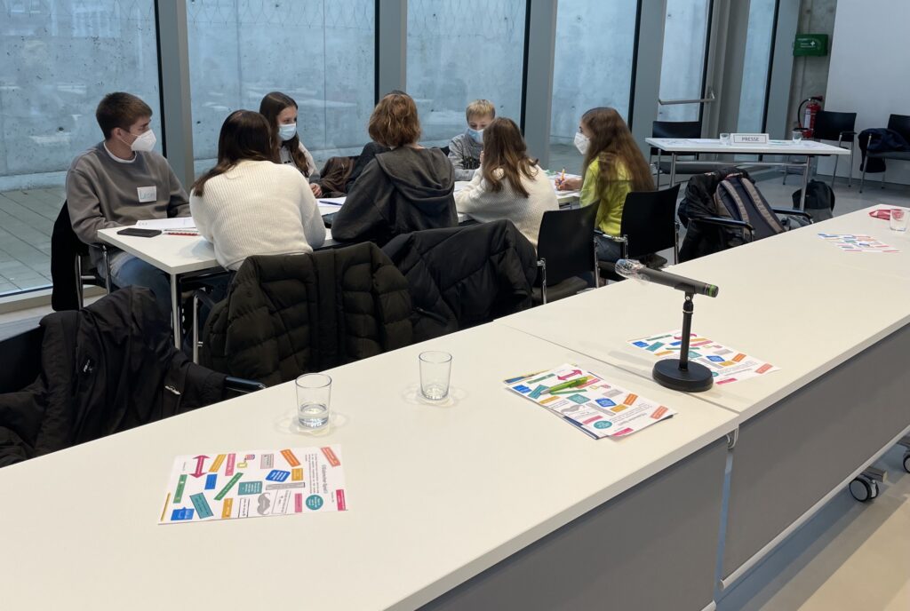 Schülerinnen und Schüler arbeiten an einem Tisch in einem modernen Klassenraum.