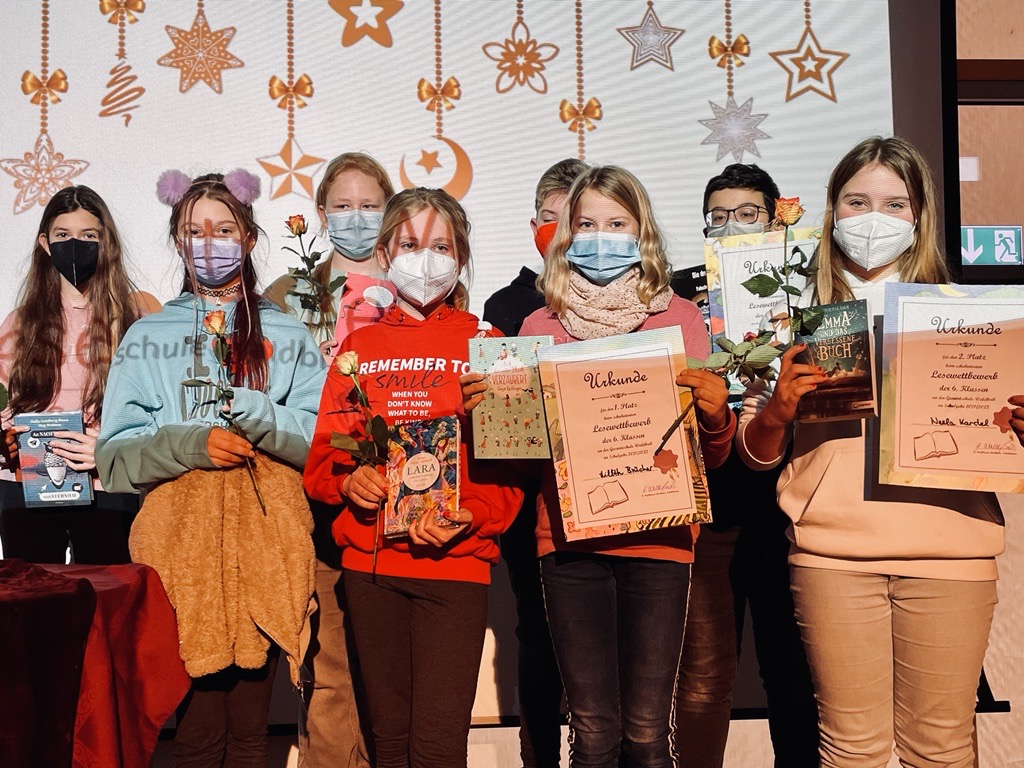 Schülerinnen und Schüler mit Auszeichnungen und Blumen auf einer Veranstaltung.