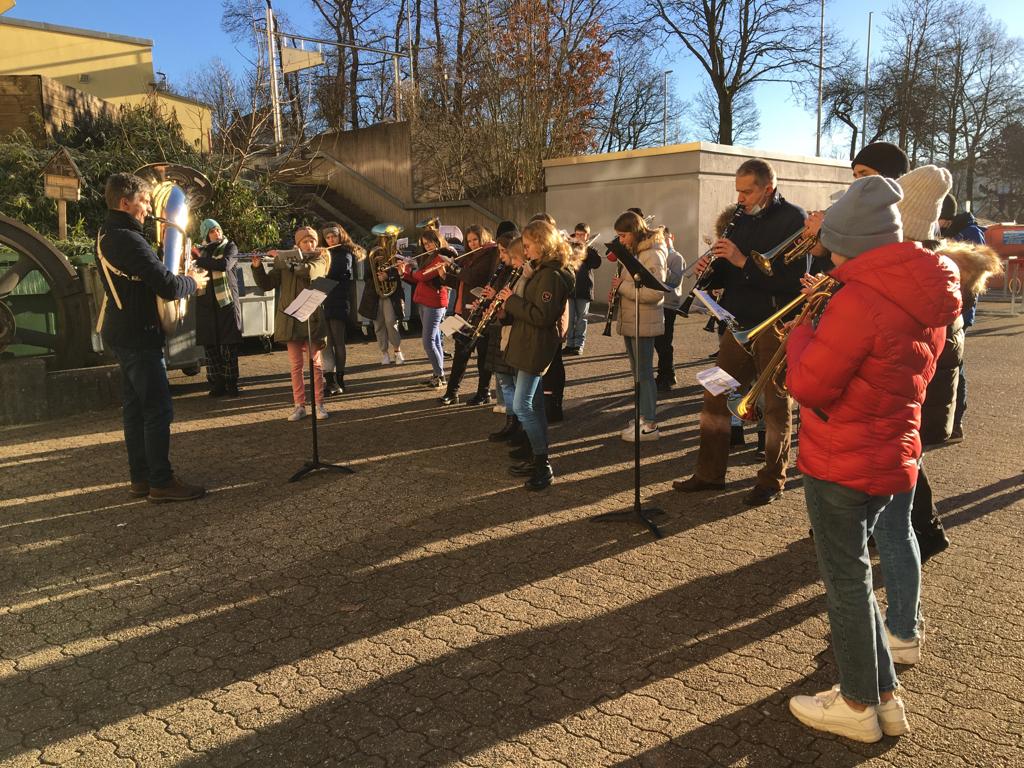 Schüler stehen im Freien und spielen gemeinsam auf Instrumenten.