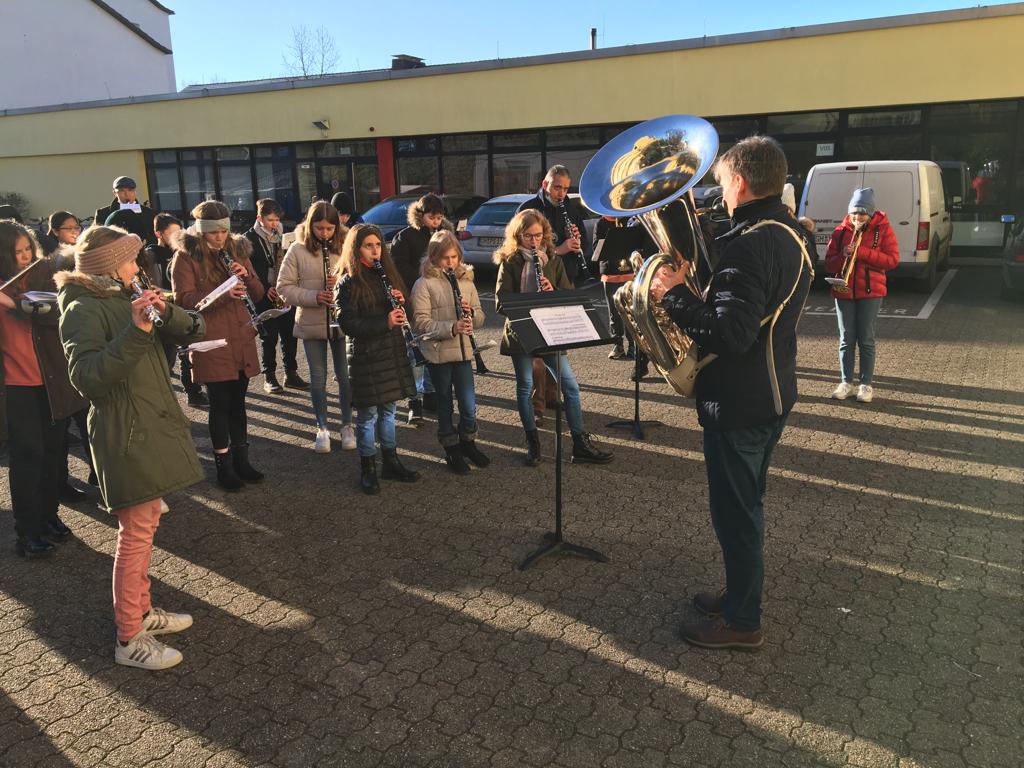 Bläsergruppe mit Tuba spielt im Freien vor Zuschauern.