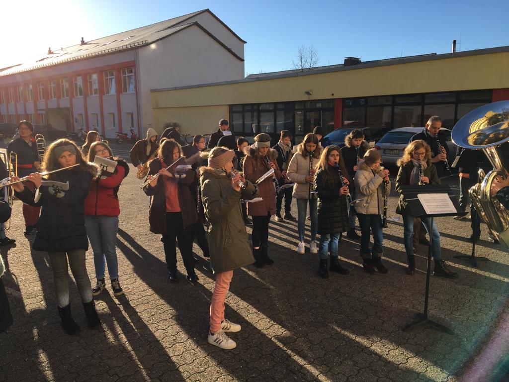 Schüler spielen Blasinstrumente in der Schulhofsonne.