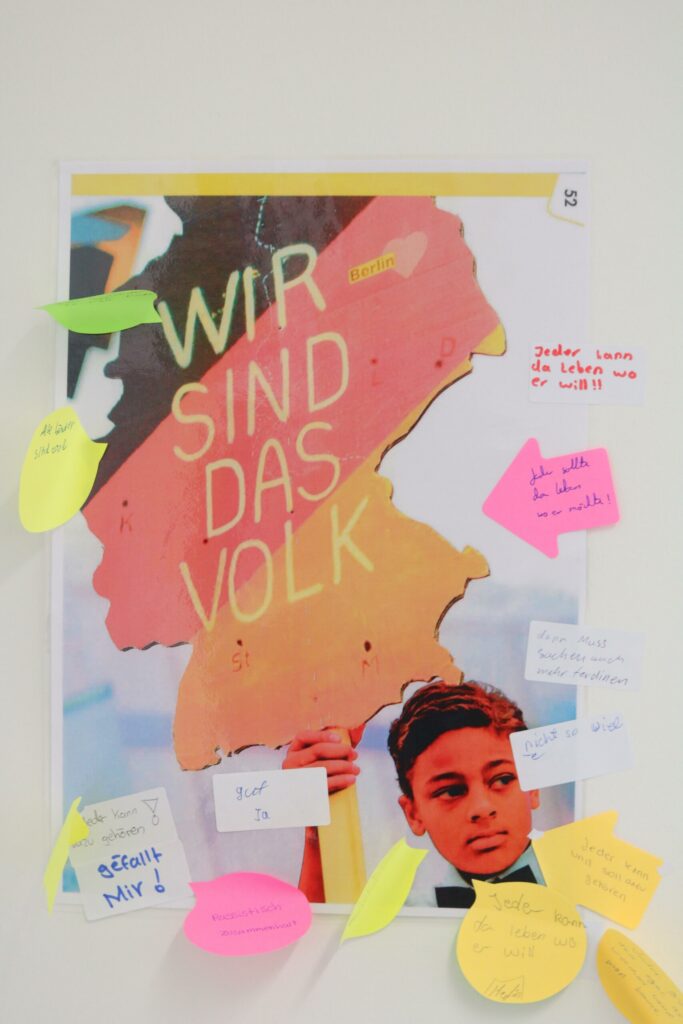 Plakat mit dem Text „WIR SIND DAS VOLK“ und Kommentaren in bunten Notizzetteln.