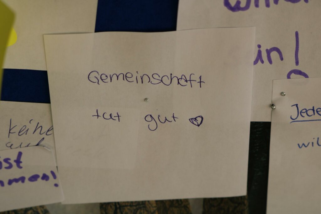Zettel mit der Aufschrift "Gemeinschaft tut gut" und Herzsymbol.