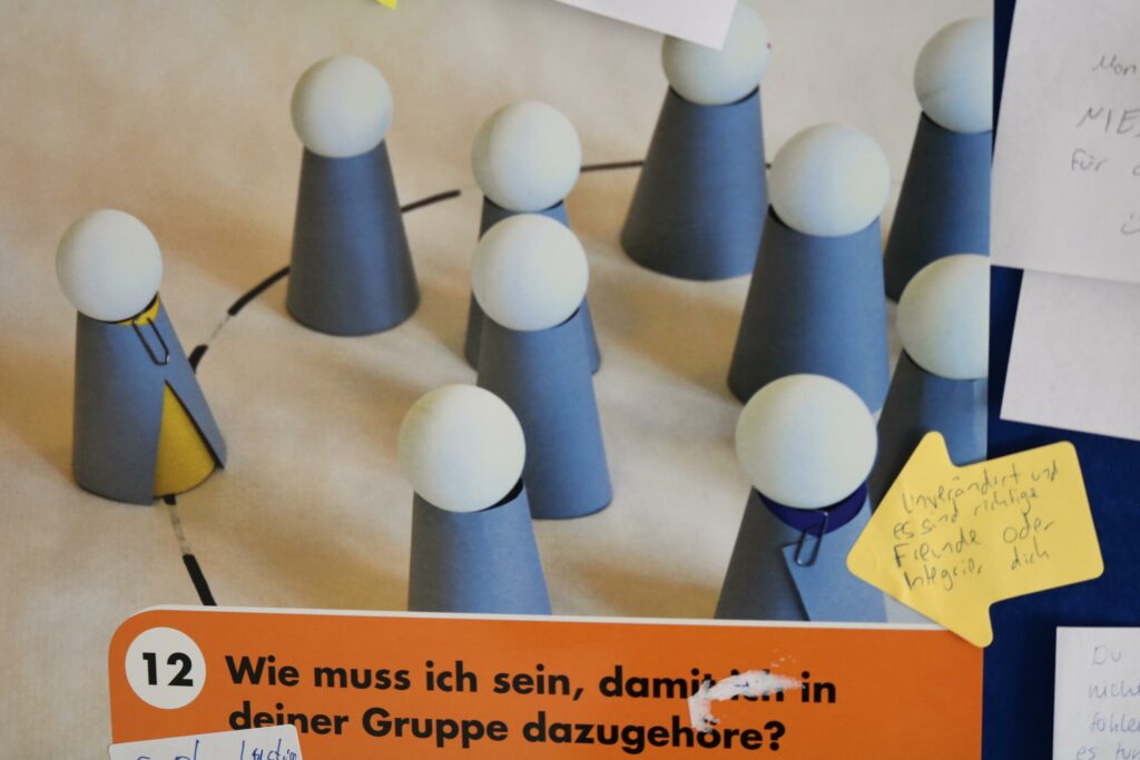 Figuren in einem Kreis, einige mit Umhängen, auf einem Plakat.