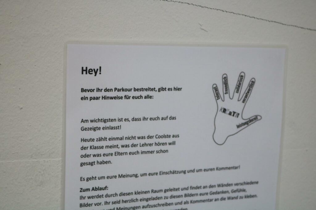 Hinweisblatt mit Anweisungen für den Parcours, Handabdruck und Informationen.