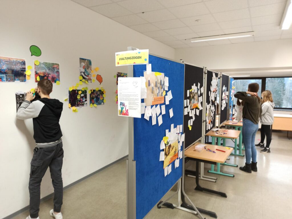 Schüler gestalten Wandtafeln mit Bildern und Notizen in einem Klassenraum.