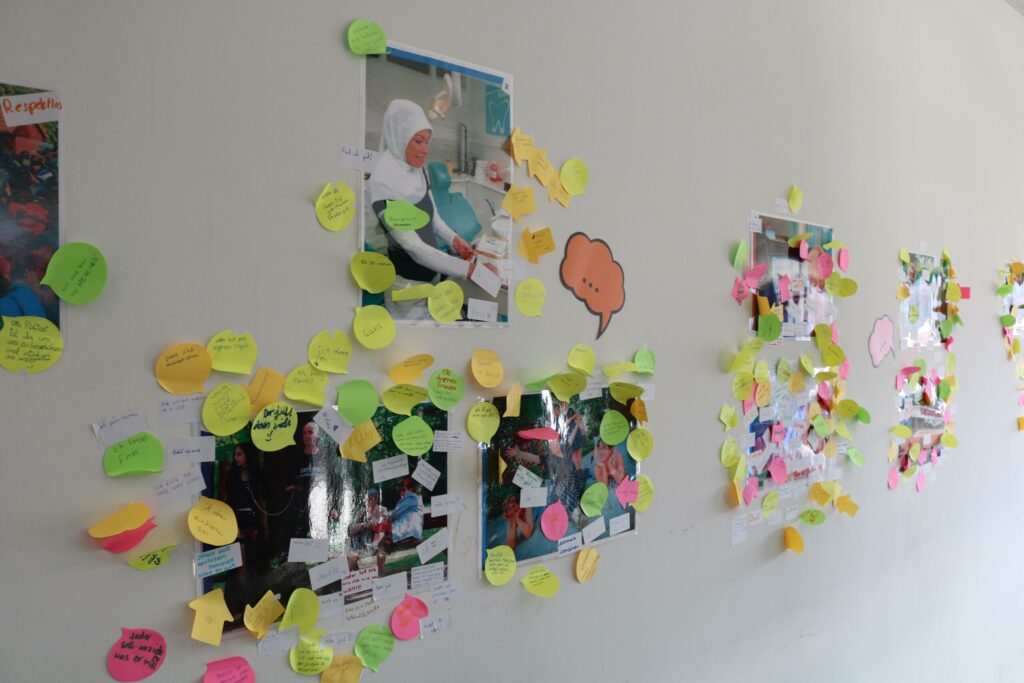 Wand mit Fotos und bunten Haftnotizen in einem Klassenzimmer.