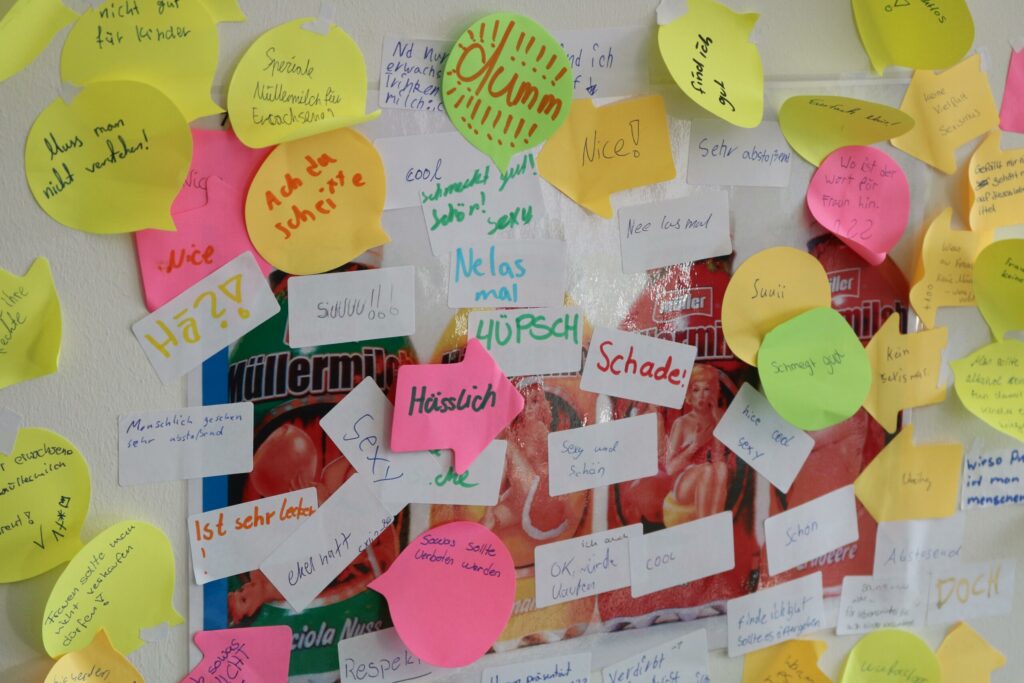 Bunte Zettel mit Notizen und Kommentaren auf einer Wand.