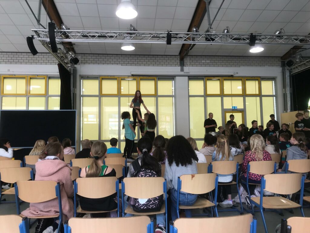 Schüler führen eine Aufführung in einem Schulgebäude vor.