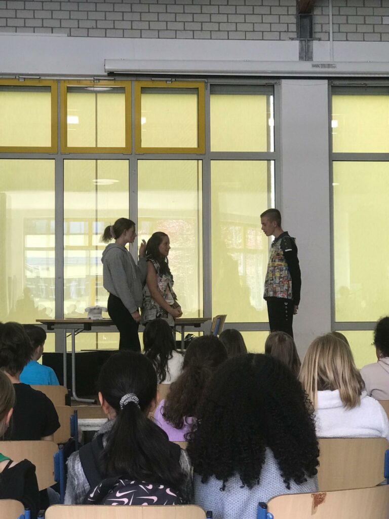 Schüler präsentieren vor einer Gruppe in einem Klassenraum.