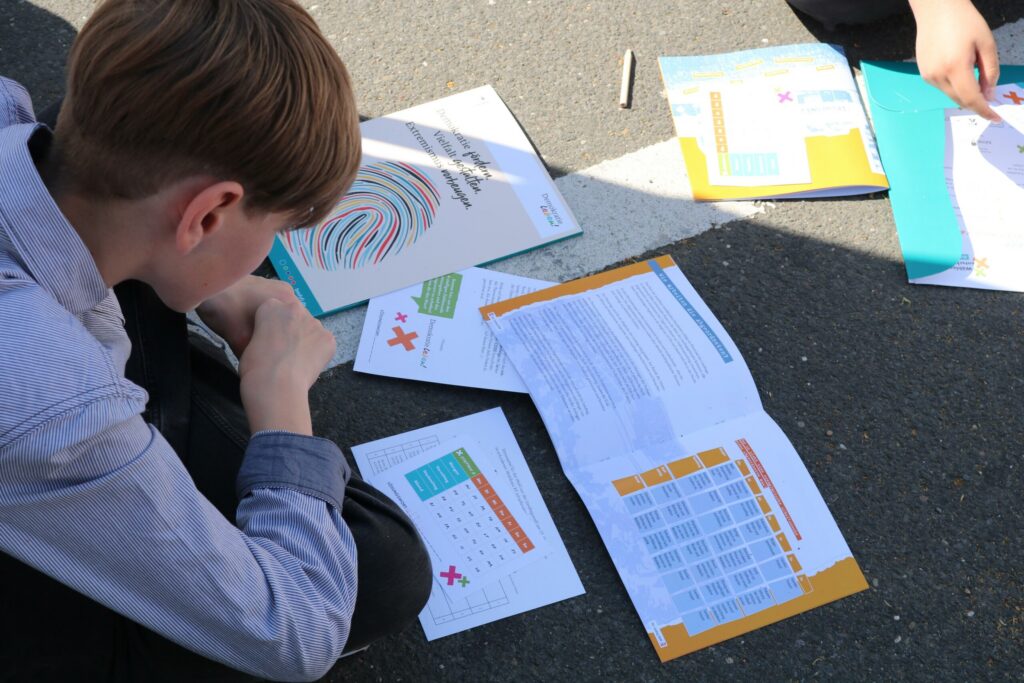 Schüler sitzt am Boden und überprüft Arbeitsblätter und Materialien.