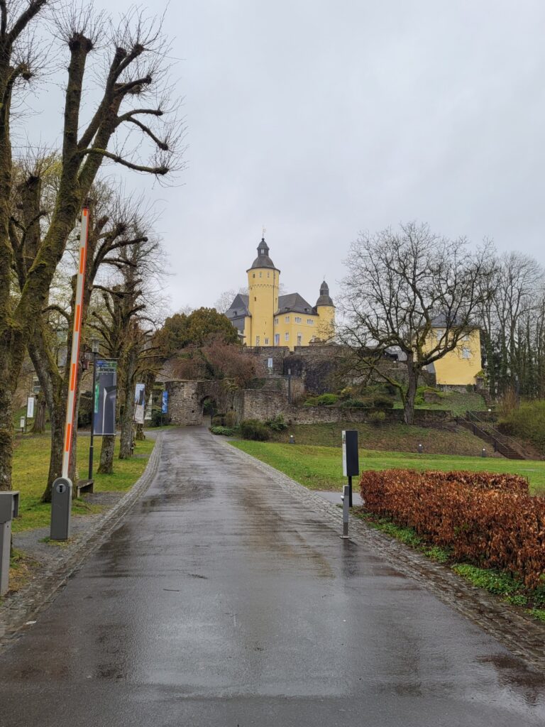Regenverhangene Straße mit Blick auf eine gelbe Burg im Hintergrund.