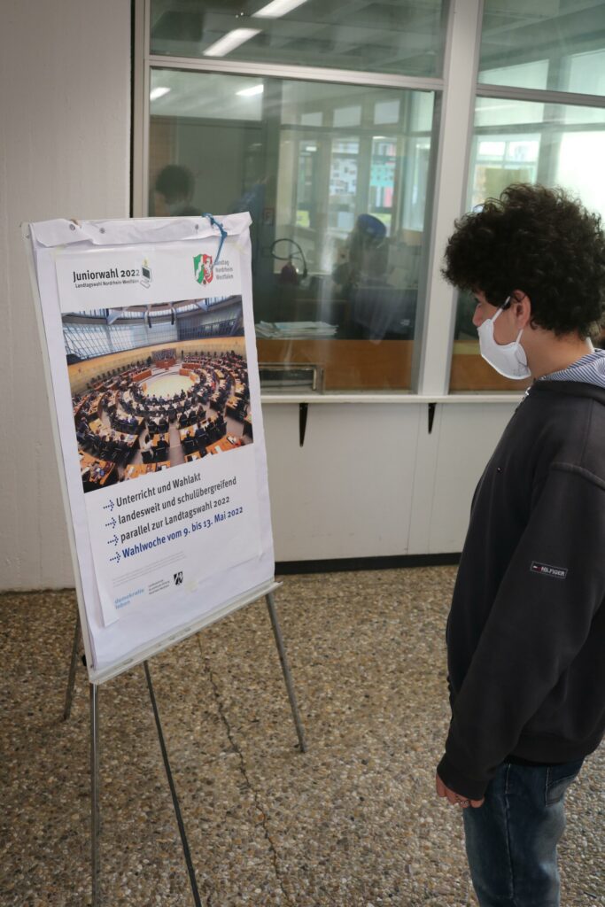 Schüler betrachtet ein Plakat mit Informationen in der Schule.