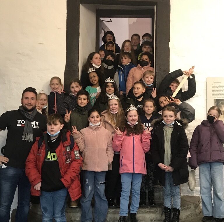 Gruppe von Schülern und Lehrern vor einem Gebäude, lächelnd und in Lärmdurchgängen.