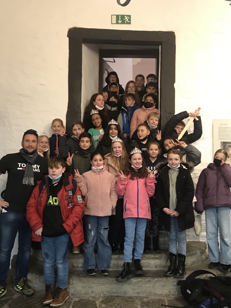 Gruppe von Schülern und Lehrern vor einem Gebäude, lächelnd und in Lärmdurchgängen.