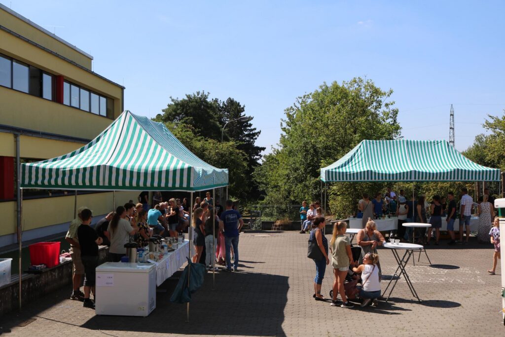 Markt mit mehreren Zelten, Menschen stehen zusammen und tauschen sich aus.
