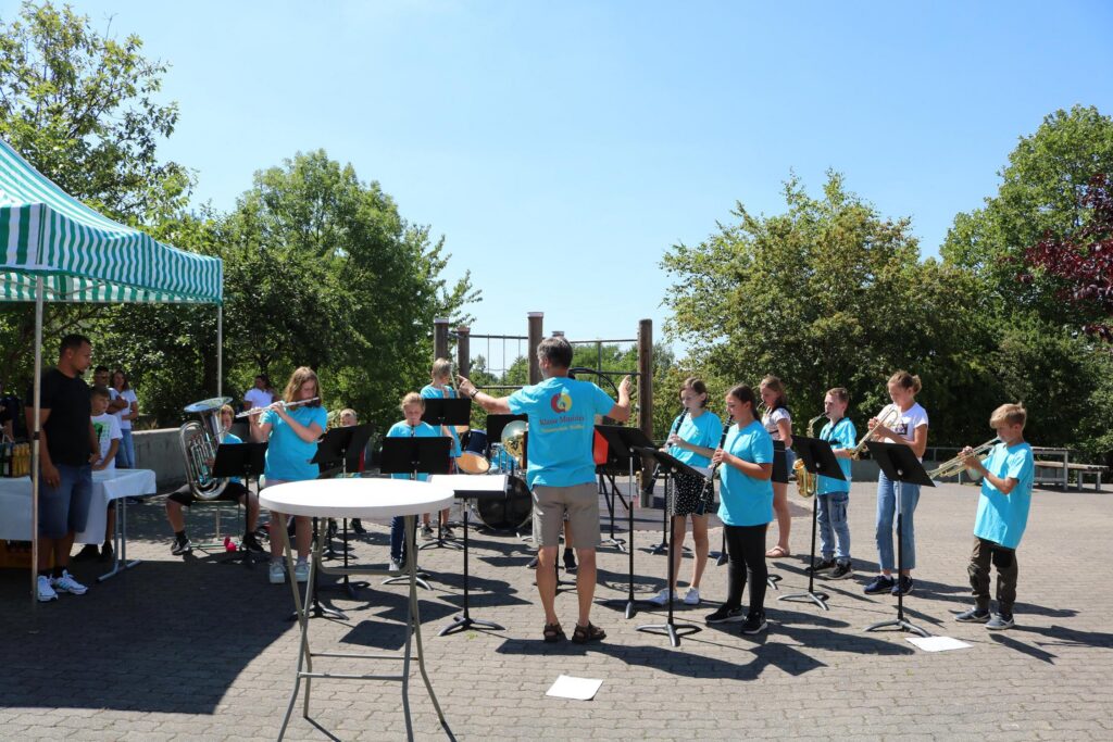 Schülerband spielt im Freien unter blauem Himmel.