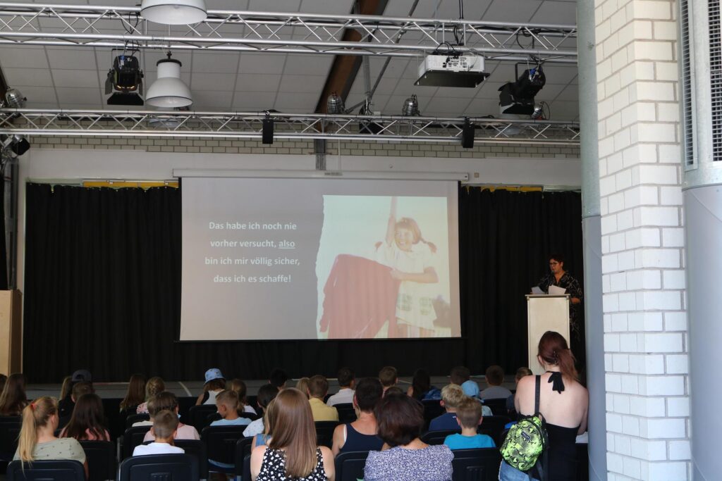 Vortrag in einem Auditorium mit Publikum und einer Präsentation auf der Leinwand.