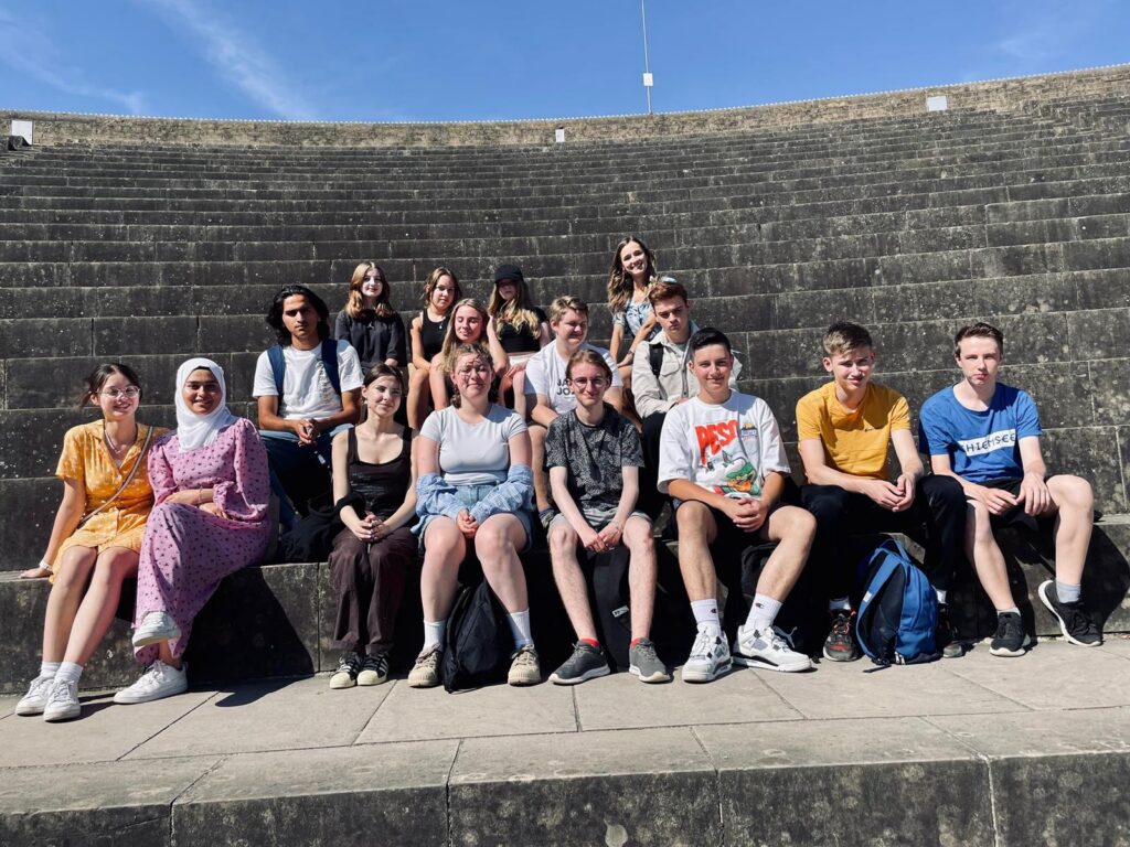 Gruppe von Schülerinnen und Schülern auf Treppen bei sonnigem Wetter.