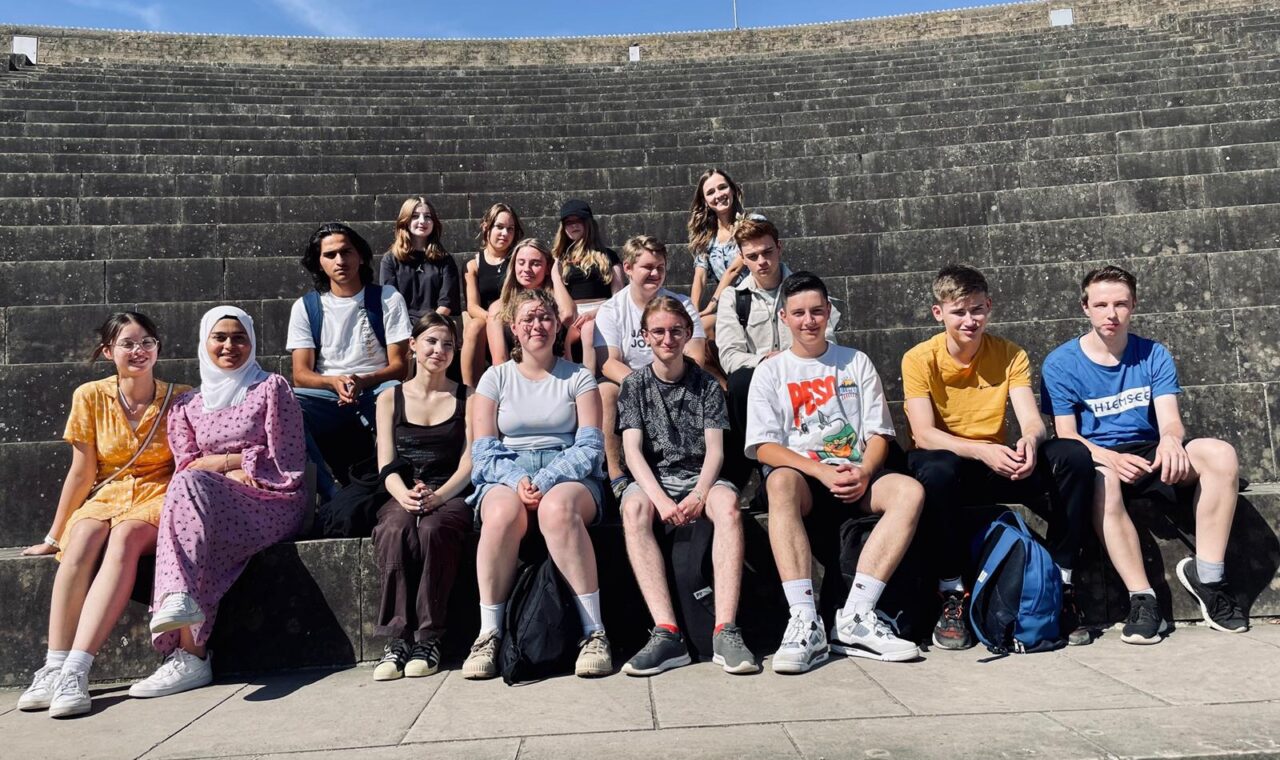 Gruppe von Schülerinnen und Schülern auf Treppen bei sonnigem Wetter.