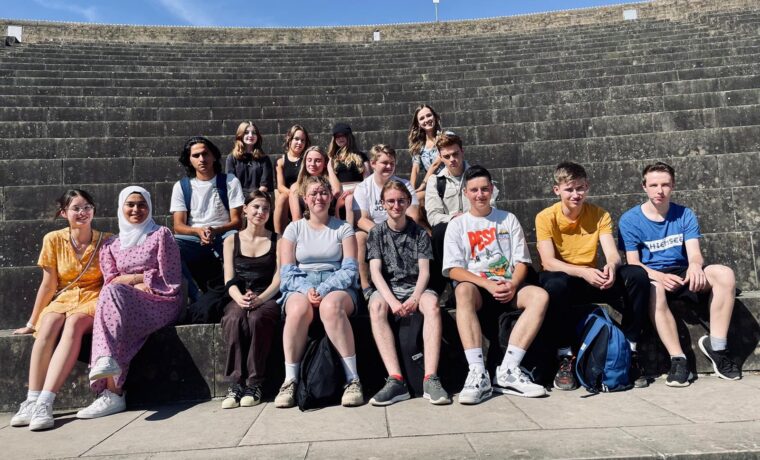 Gruppe von Schülerinnen und Schülern auf Treppen bei sonnigem Wetter.