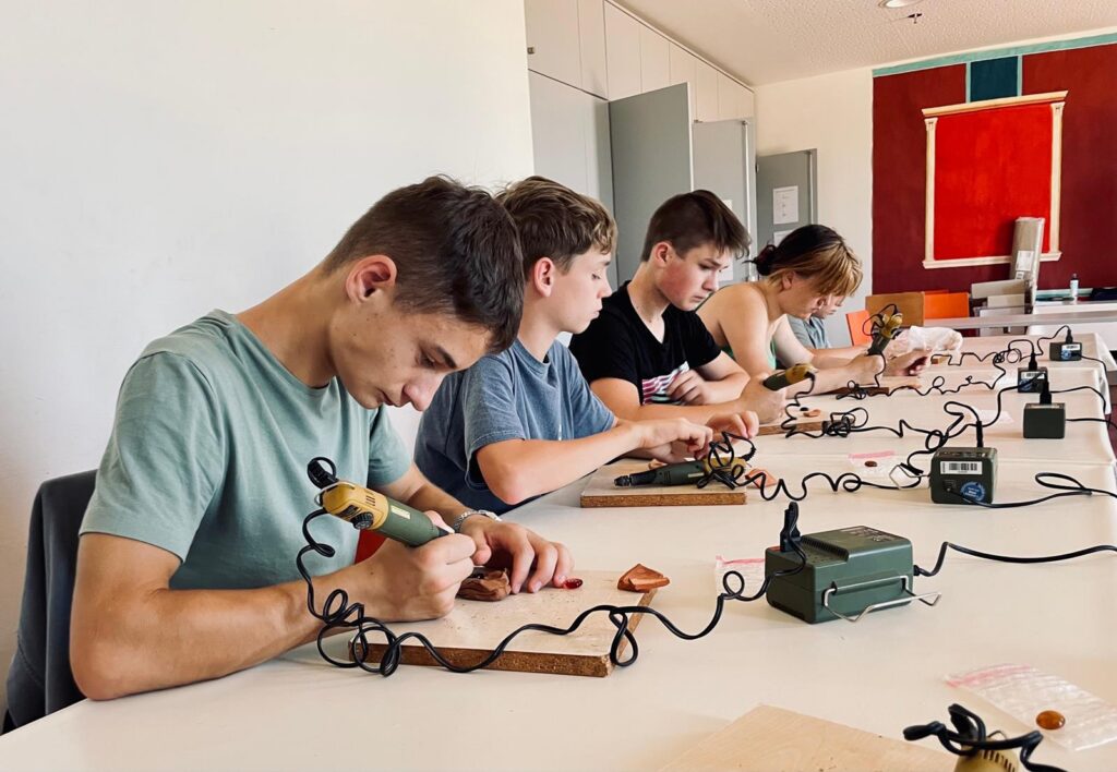 Schüler arbeiten an Elektronikprojekten mit Lötgeräten an einem Tisch.