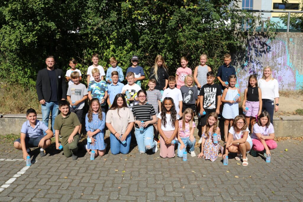 Gruppe von Schülerinnen und Schülern steht im Freien, umgeben von Bäumen.