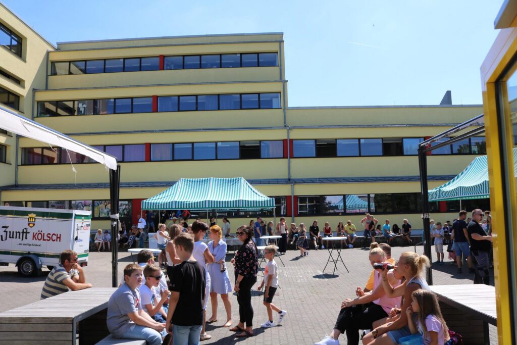 Schüler und Lehrer versammeln sich auf dem Pausenhof vor der Schule.