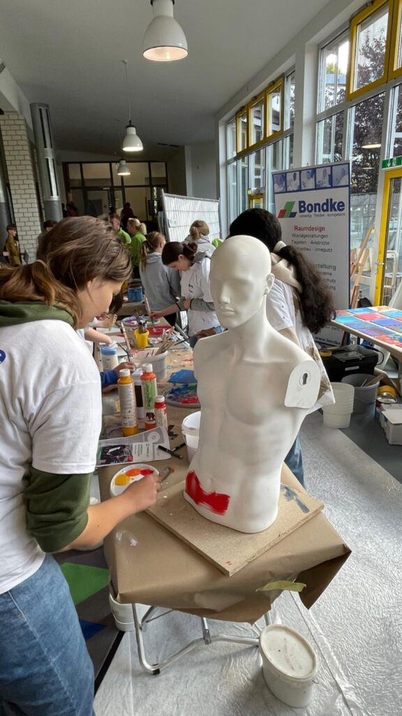 Schülerinnen gestalten Figuren an einem Tisch in einem kreativen Workshop.