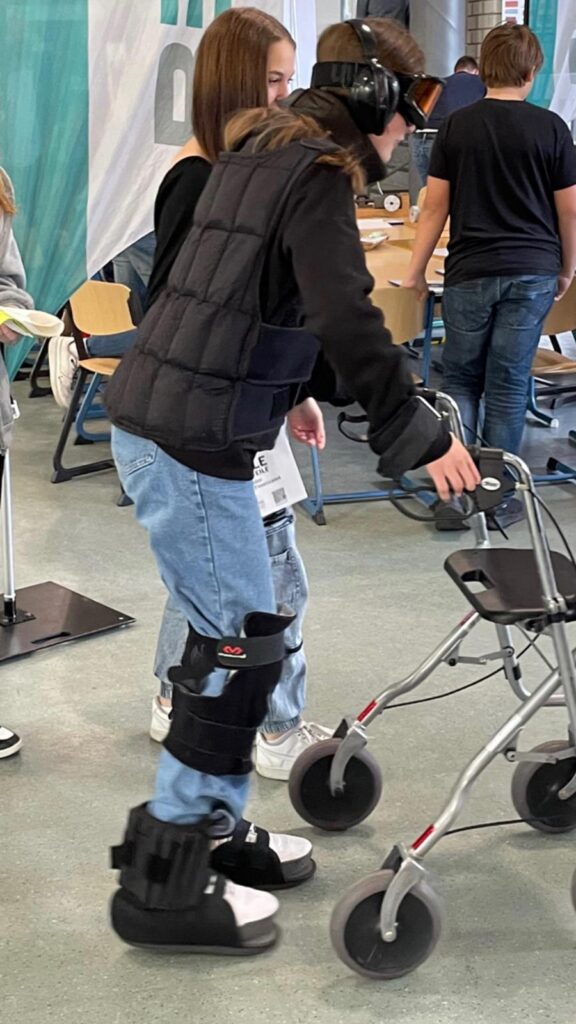 Schüler mit Gehhilfen und speziellen Schuhen in einem Klassenzimmer.