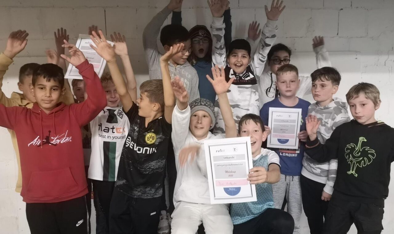 Gruppe von Kindern in einem Raum, die fröhlich mit Zertifikaten posieren.