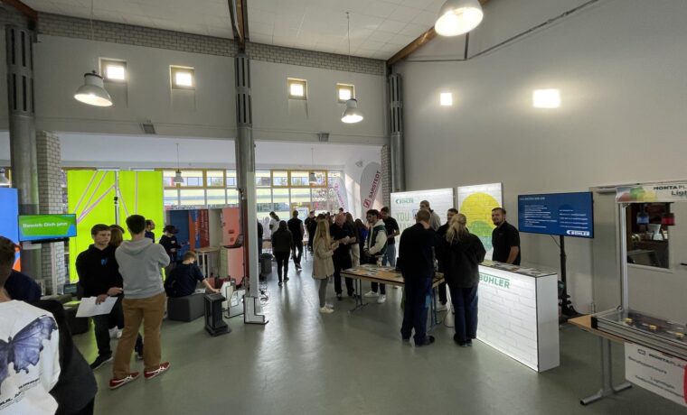 Messe mit mehreren Ständen und Besuchern in einem großen Raum.