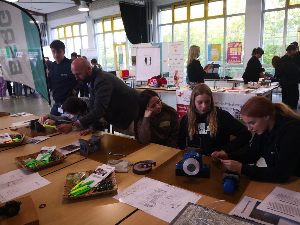 Schüler und Lehrer arbeiten an Projekten an einem Tisch in einem Klassenzimmer.