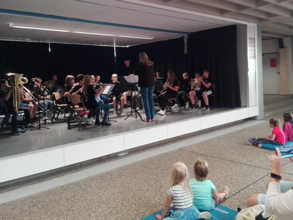 Schüler spielen in einem Musikensemble, Zuschauer sitzen im Vordergrund.