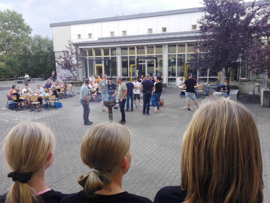 Schüler beobachten eine Veranstaltung im Hof der Schule.