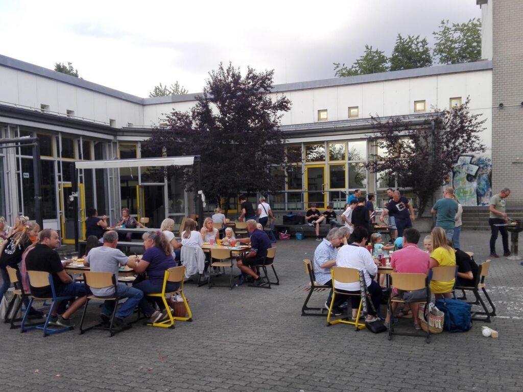 Menschen sitzen an Tischen im Freien und genießen eine gemeinsame Veranstaltung.