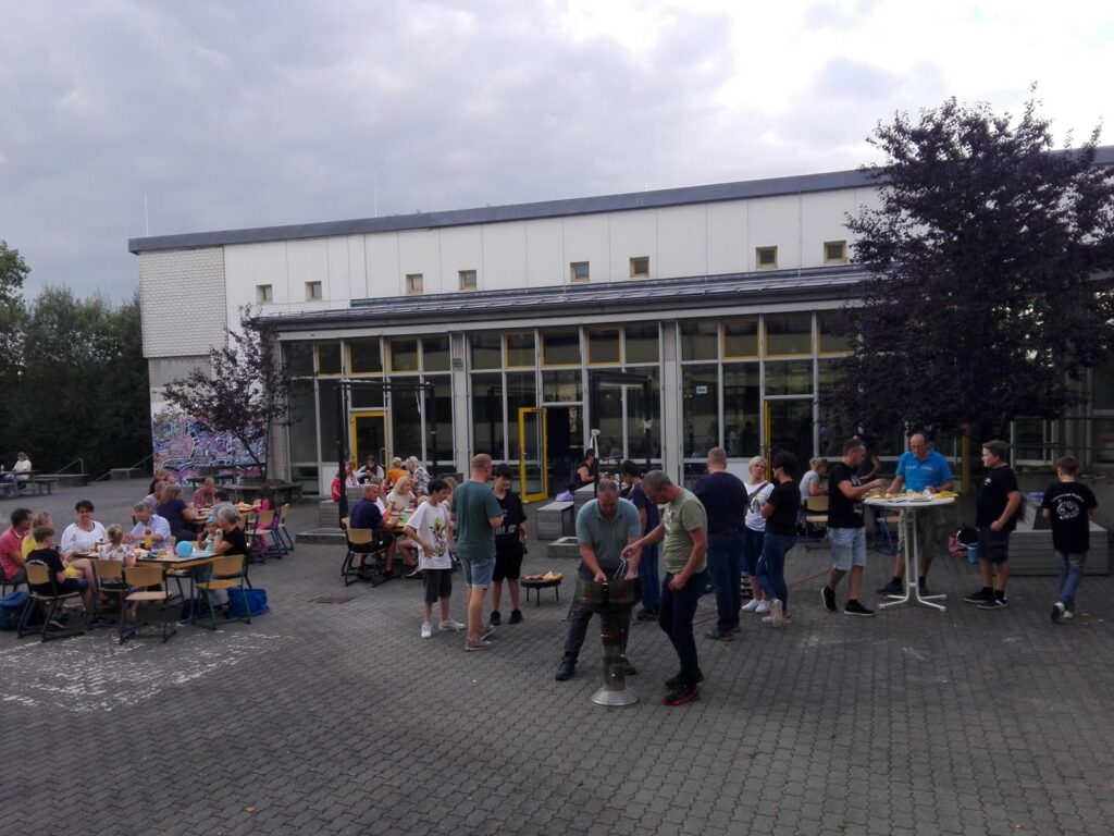 Schüler stehen in Gruppen vor einem Schulgebäude und unterhalten sich.