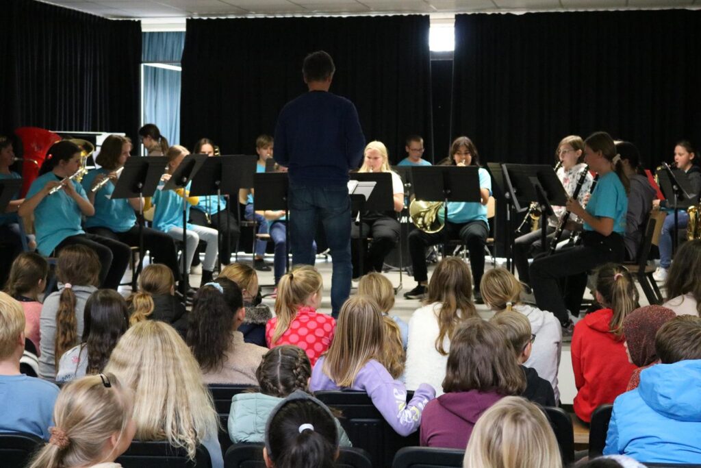 Schülerband spielt vor Publikum in einem Saal.