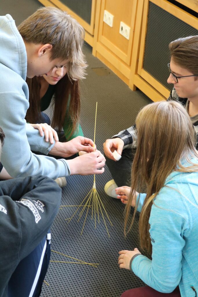 Schüler arbeiten zusammen an einem Projekt mit Strohhalmen.