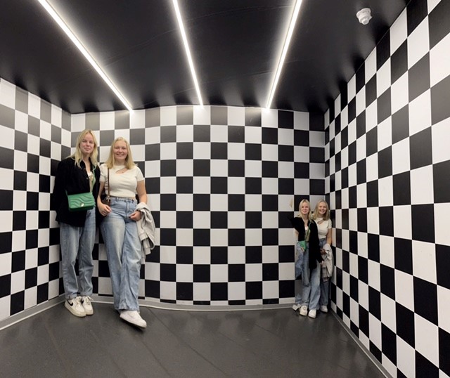 Zwei Frauen stehen in einem Raum mit schwarz-weißen Schachbrettwänden.