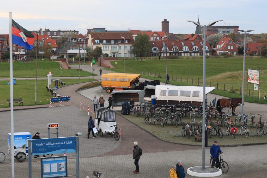 Blick auf einen Platz mit Fahrrädern, einem Pferd und einem gelben Lieferwagen.