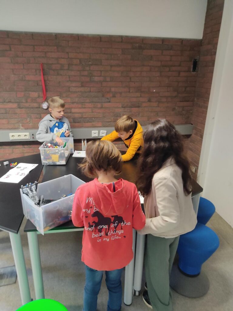 Kinder arbeiten an einem Tisch mit Bastelmaterialien und Notizen.