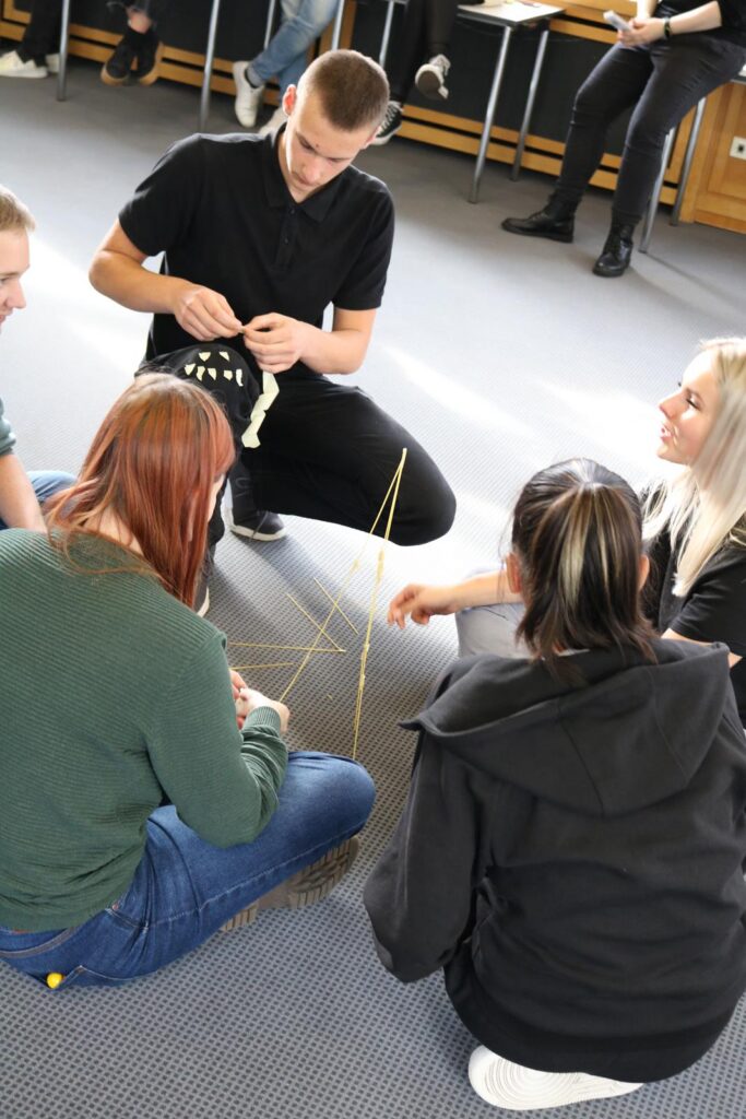 Gruppendiskussion mit Studenten, die gemeinsam eine Konstruktion bauen.