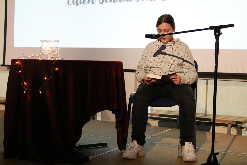 Ein Schüler sitzt an einem Tisch und liest aus einem Buch.